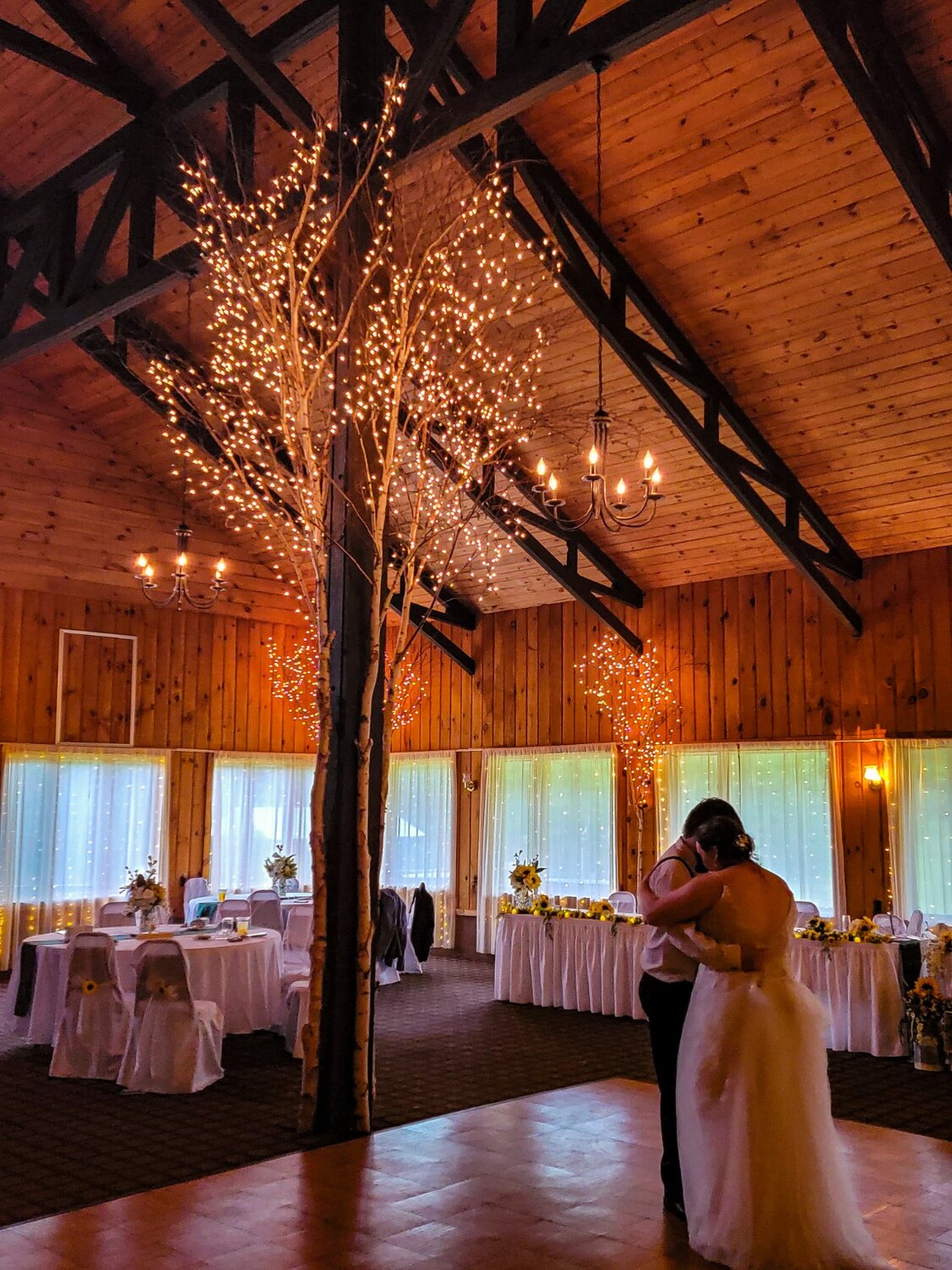 Couple dancing beneath warm lights in a barn