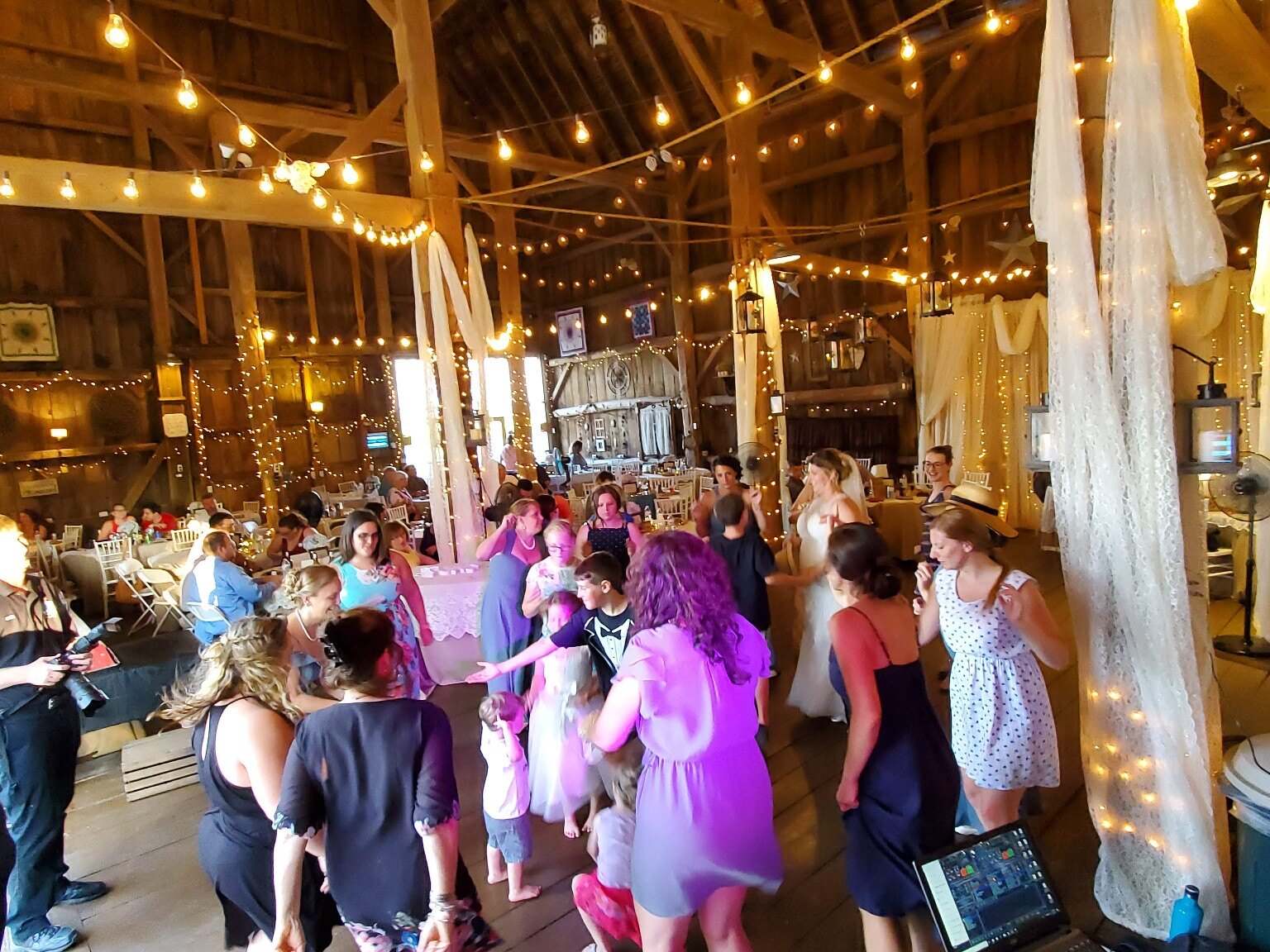 Guests dancing beneath barn string lights