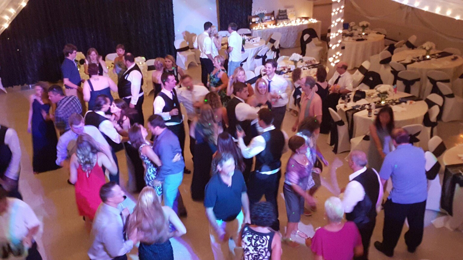 A full wedding dance floor beneath warm string lights