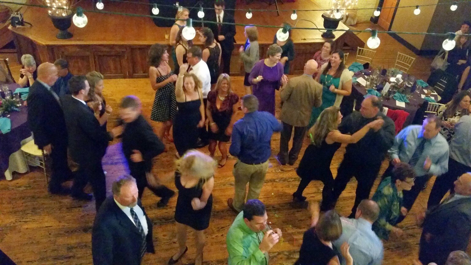 Guests dancing in an elegant reception space with wood floors