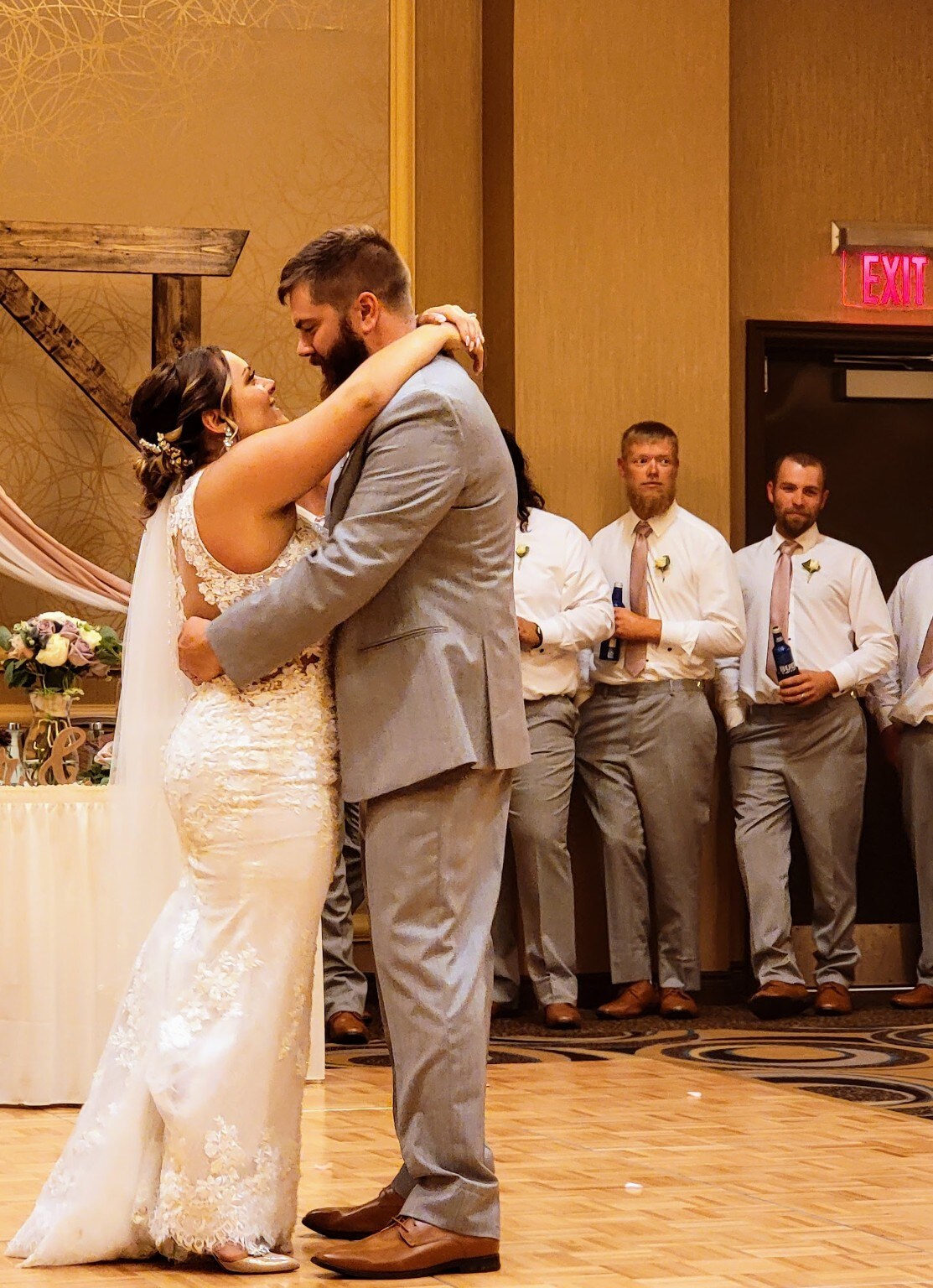 Newlyweds sharing their first dance surrounded by their wedding party